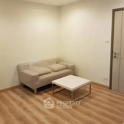 Minimalist living room with modern sofa and coffee table on wooden flooring.
