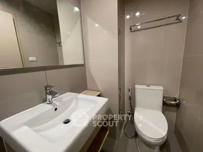Modern bathroom with sleek fixtures and neutral tiles, featuring a spacious sink and toilet.