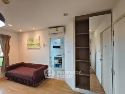 Cozy living room with wooden flooring, sofa, and open kitchen view in modern apartment.