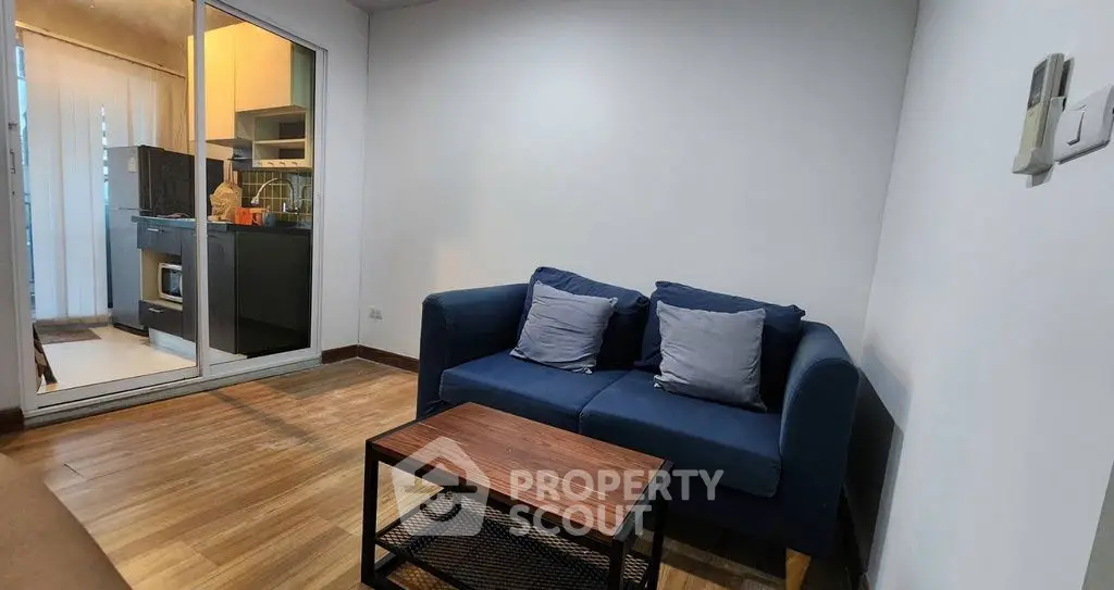 Modern living room with cozy blue sofa and open kitchen layout