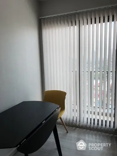 Modern study room with sleek black desk and yellow chair by large window with vertical blinds.