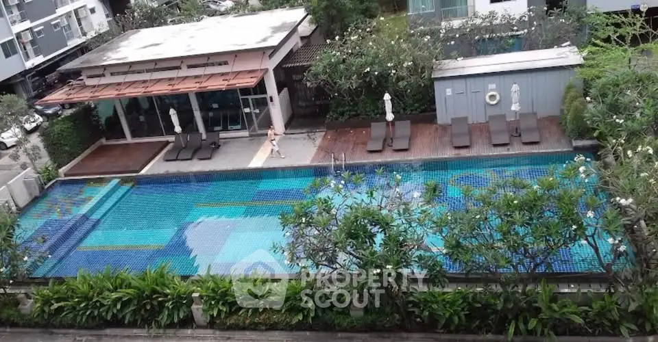 Luxurious residential swimming pool with lush greenery and modern design.