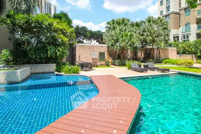 Luxurious residential pool area with lush greenery and sun loungers, perfect for relaxation.