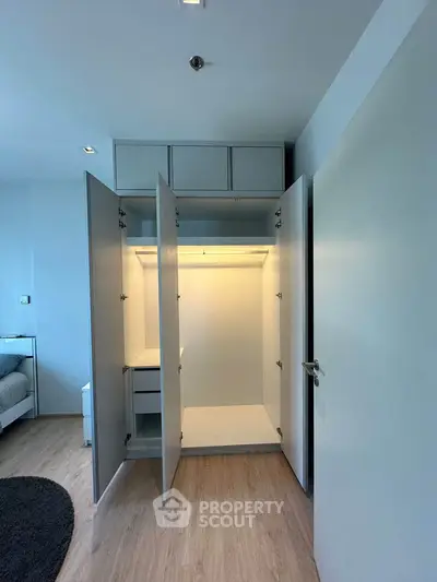 Spacious modern wardrobe with open doors in a bright bedroom setting.