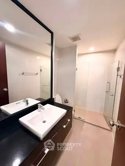 Modern bathroom with sleek fixtures and glass shower enclosure in a contemporary home.