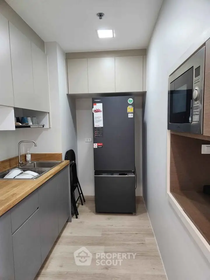 Modern kitchen with sleek appliances and wooden countertops in a compact layout.