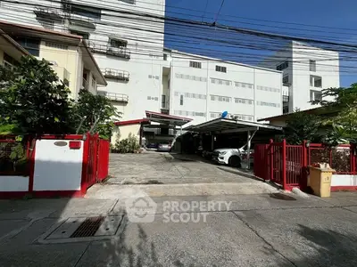 Spacious parking area in front of modern residential building with secure gated entrance.