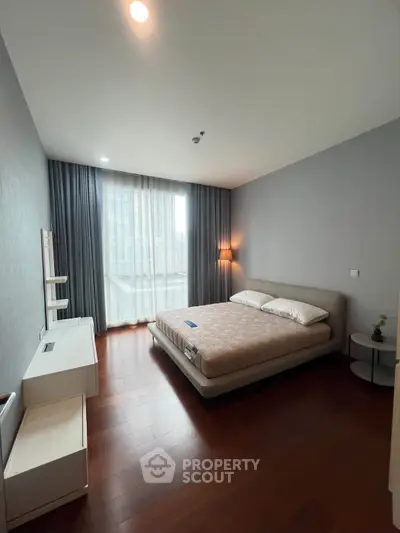 Spacious modern bedroom with large window and elegant furnishings in a luxury apartment.