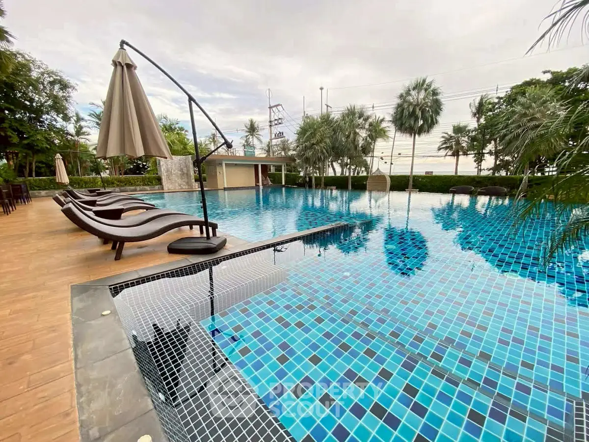Luxurious outdoor swimming pool with stylish loungers and umbrellas, surrounded by lush greenery.