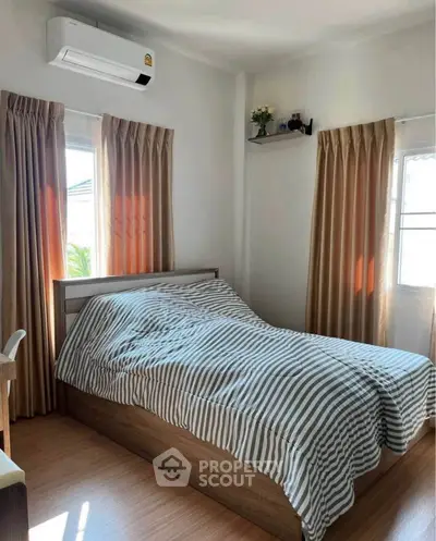 Cozy bedroom with natural light and modern air conditioning unit, perfect for relaxation.