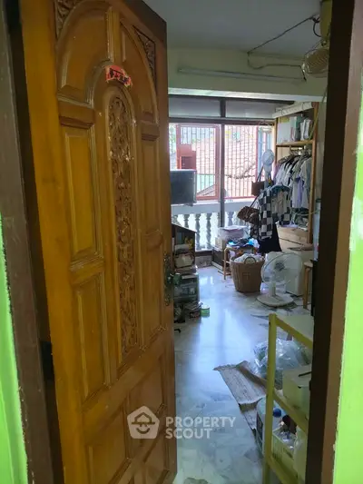 Cozy interior view of a cluttered room with wooden door and balcony access, ideal for creative renovation.