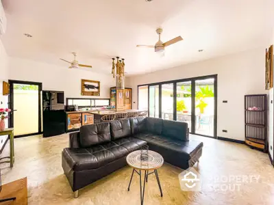 Spacious living room with modern black leather sofa and open kitchen layout