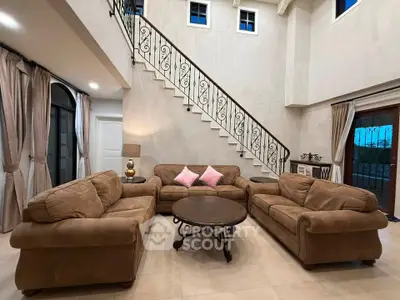 Luxurious living room with high ceilings and elegant staircase in a spacious home.