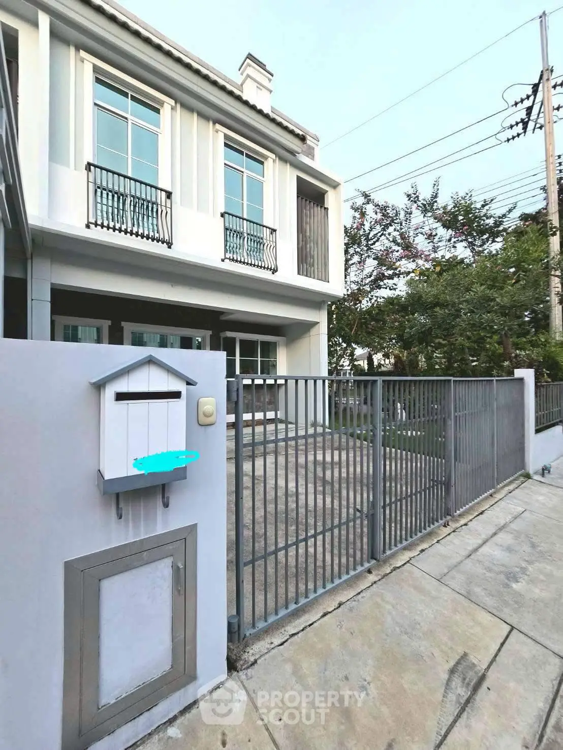 Modern two-story house with gated driveway and balcony