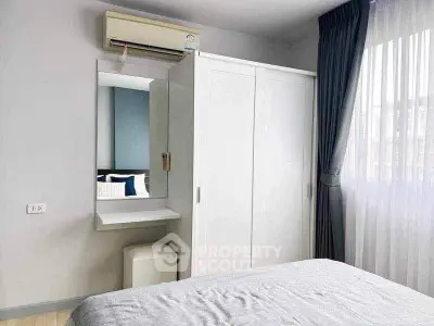 Cozy bedroom with built-in wardrobe and natural light from large window.