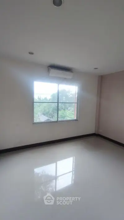 Spacious empty room with large window and air conditioning unit
