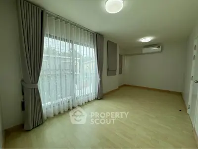 Spacious empty room with large window and air conditioning, perfect for customization.