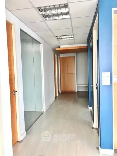 Modern office hallway with glass partitions and wooden doors