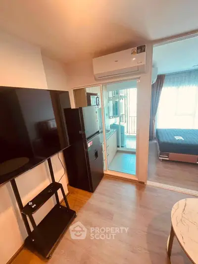 Modern apartment interior with TV, fridge, and air conditioning, featuring a cozy bedroom and stylish decor.