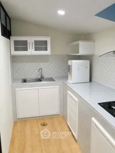 Modern compact kitchen with sleek white cabinets and gas stove