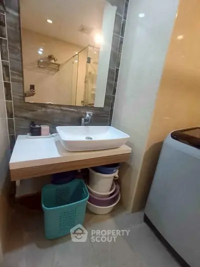 Modern bathroom with stylish sink and washing machine, featuring practical storage solutions.