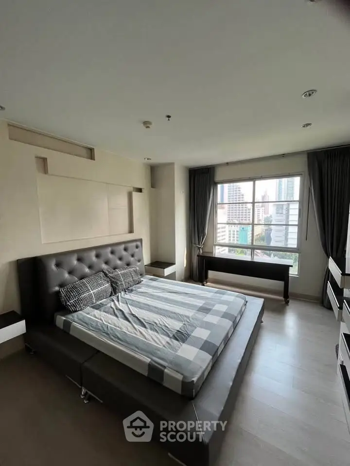 Spacious bedroom with modern decor and city view, featuring a large bed and ample natural light.