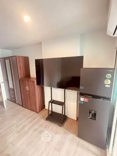 Modern living space with sleek TV, stylish cabinets, and a contemporary fridge.