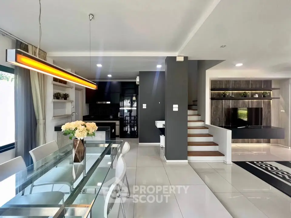 Modern open-plan living room with sleek kitchen and stylish dining area, featuring contemporary lighting and elegant decor.