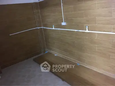 Unfinished room with tiled walls and exposed plumbing, potential for customization.