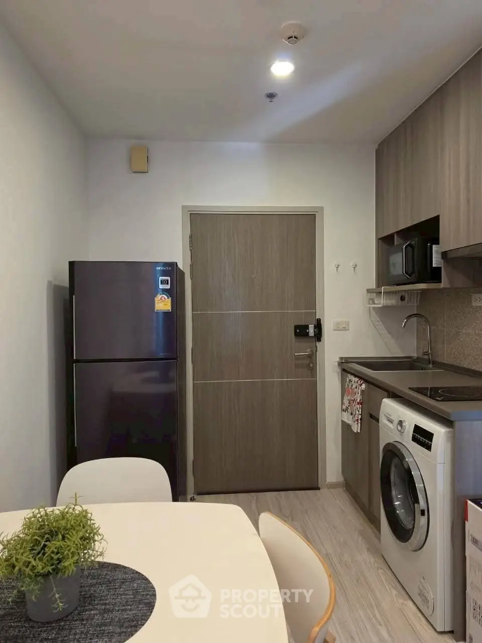 Modern kitchen with washing machine and fridge in compact apartment