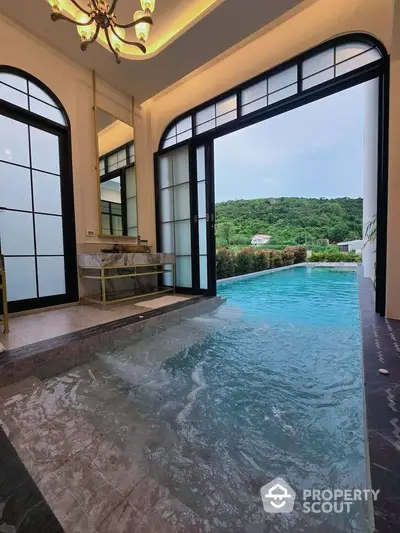 Luxurious indoor pool with stunning mountain view through elegant arched windows and doors.