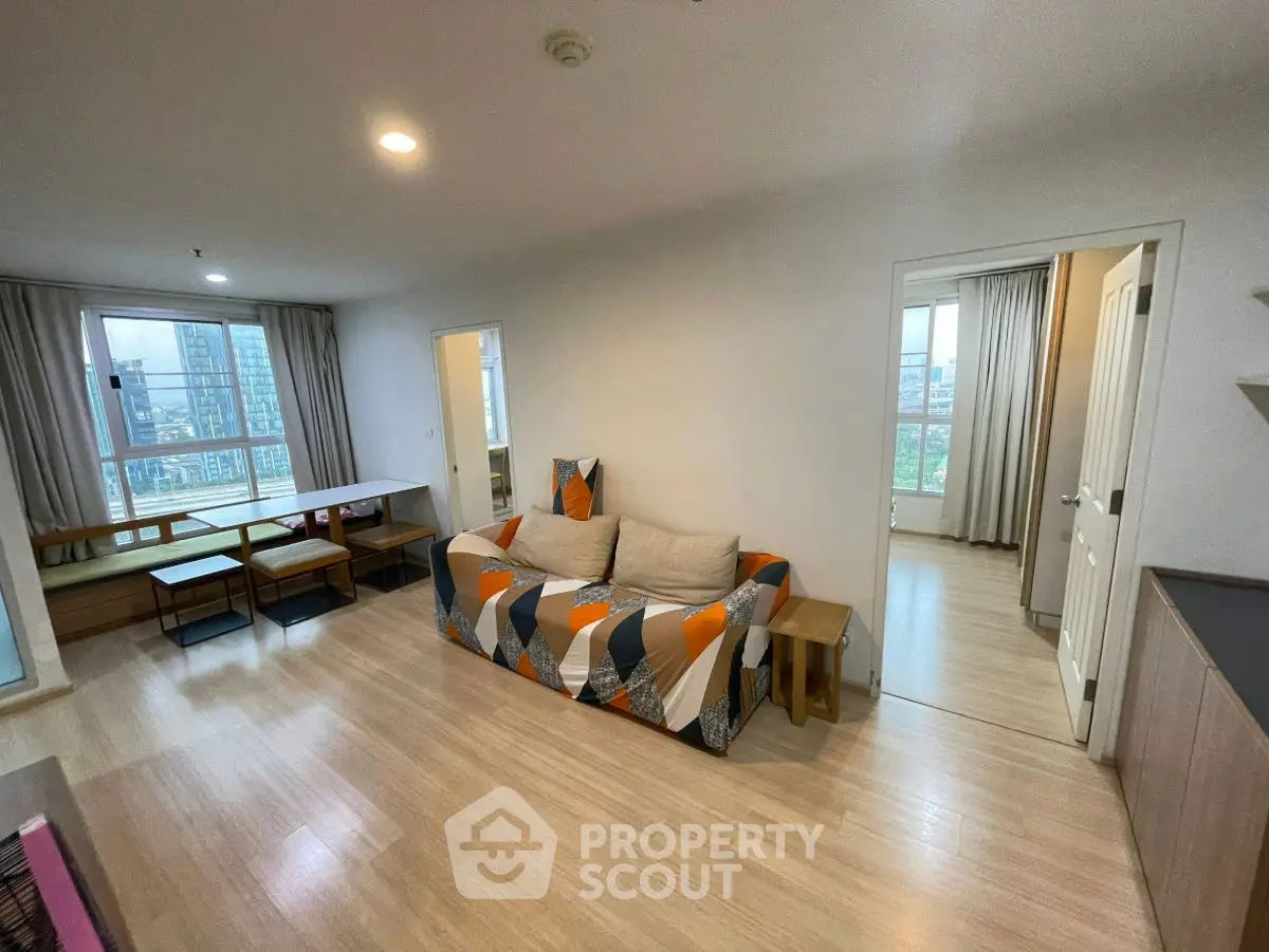 Modern living room with stylish sofa and large windows offering city views.