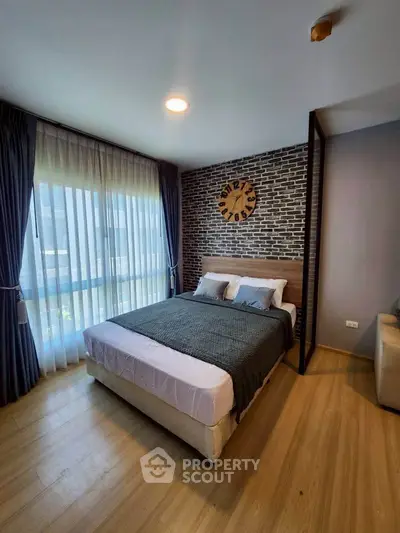 Modern bedroom with stylish brick accent wall and large window for natural light.