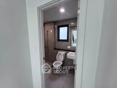 Modern bathroom with sleek design, featuring a toilet, sink, and shower area.