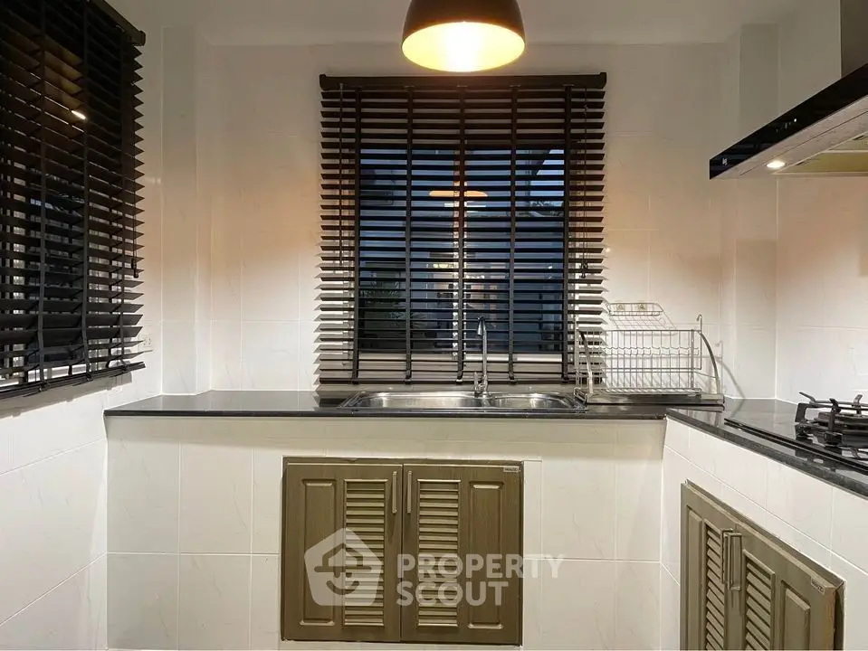 Modern kitchen with sleek countertops and stylish blinds, featuring a gas stove and double sink.
