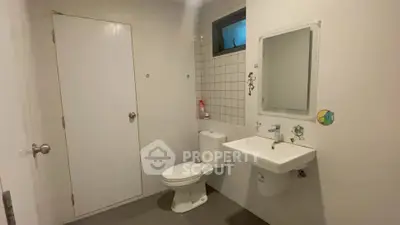 Modern minimalist bathroom with white fixtures and tiled wall accent.