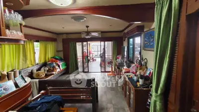 Spacious living room with large windows and sliding doors leading to patio, featuring cozy seating and vibrant decor.