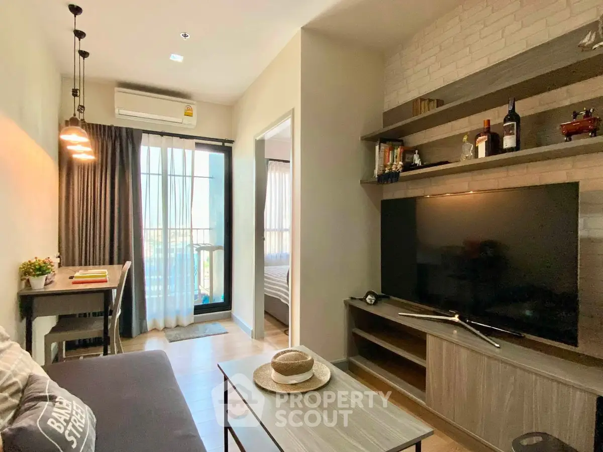 Modern living room with stylish decor and large TV, adjacent to a cozy bedroom with natural light.