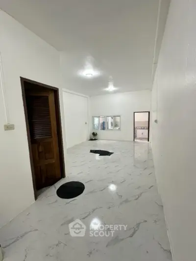 Spacious interior with marble flooring and wooden door, ideal for modern living.