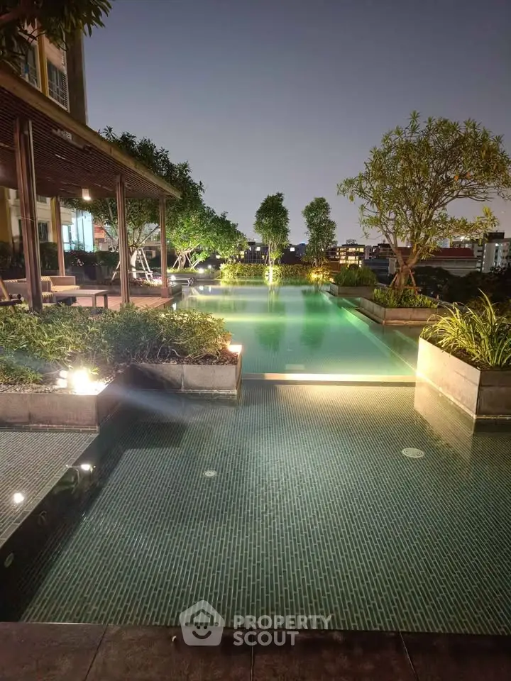 Luxurious rooftop pool with ambient lighting and lush greenery at night.