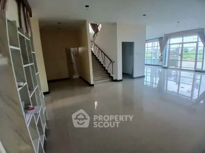 Spacious open-plan living room with large windows and staircase in modern home