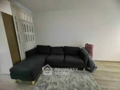 Cozy living room with modern dark sofa and plush rug on wooden floor