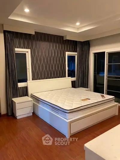 Spacious bedroom with modern design and elegant wallpaper, featuring a comfortable bed and ample natural light.