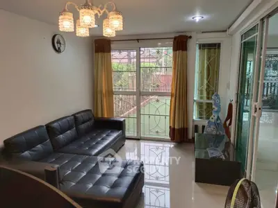 Spacious living room with modern black leather sofa and elegant chandelier