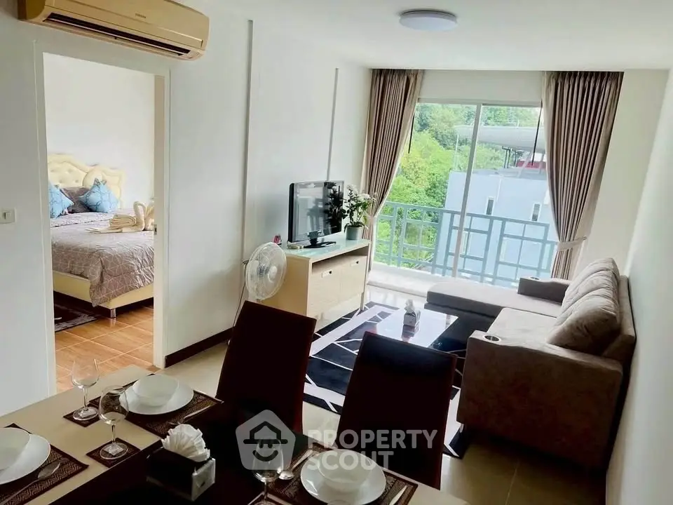 Modern living room with balcony view, stylish furniture, and open layout connecting to bedroom.