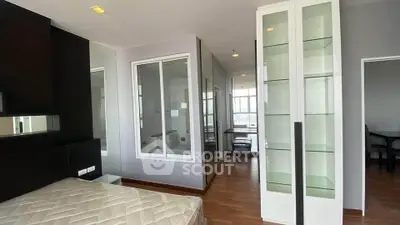 Modern bedroom with glass shelving and hardwood floors in a stylish apartment.