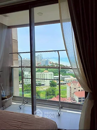 Stunning high-rise bedroom view with balcony overlooking cityscape and ocean.