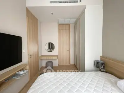 Modern bedroom with minimalist design, featuring a wall-mounted TV and sleek wooden furniture.