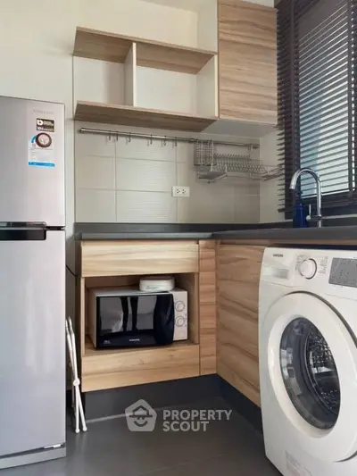 Modern kitchen with wooden cabinets, washing machine, and microwave in a compact layout.
