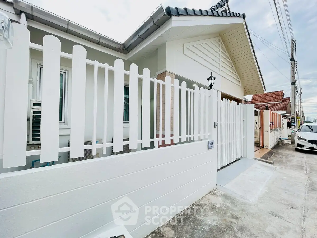 Charming suburban home with white picket fence and modern roof design.